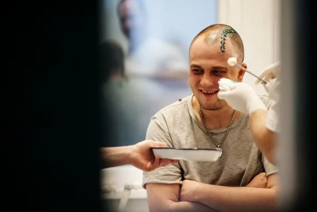 A smiling patient with a bandaged head after surgery
