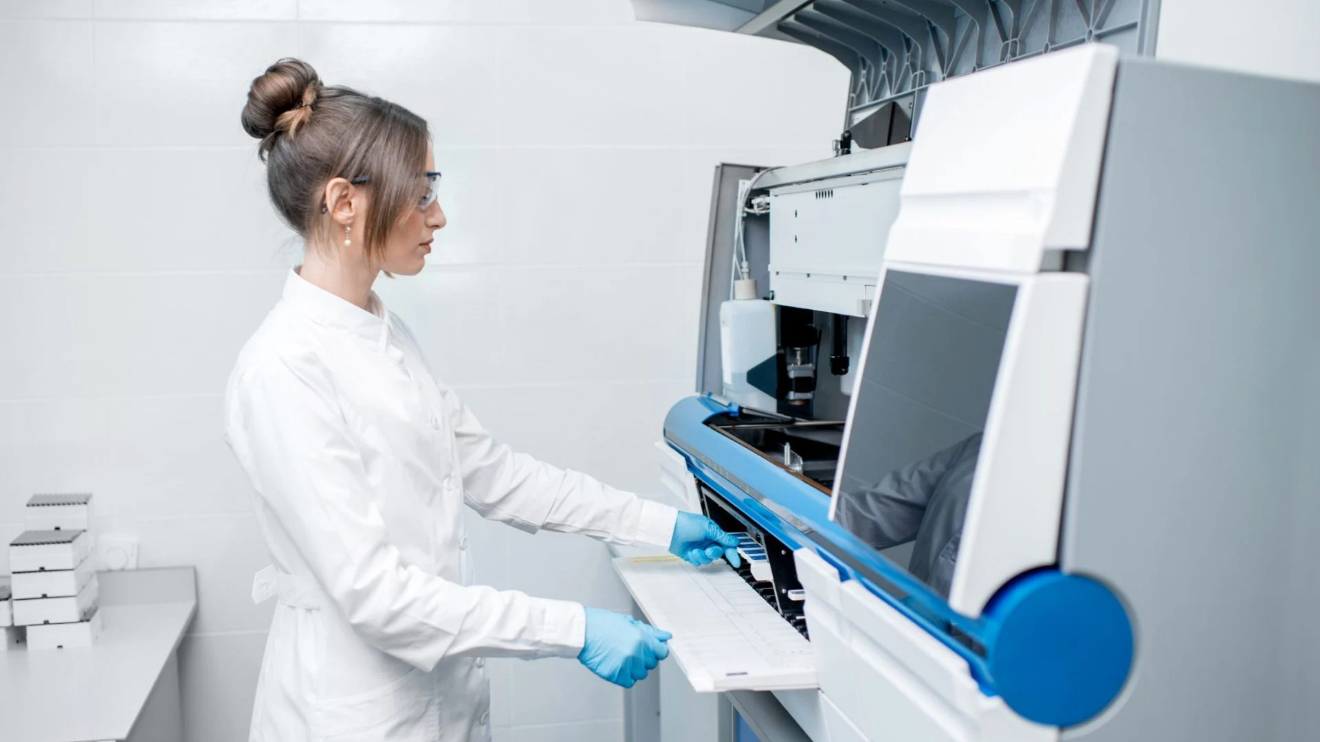 A scientist loading samples into a laboratory analyser